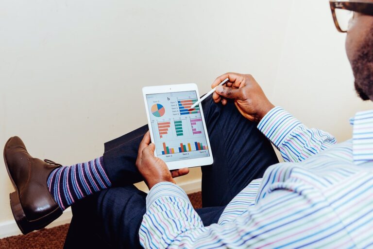 Person in striped socks using a stylus on a tablet displaying colorful charts and graphs.