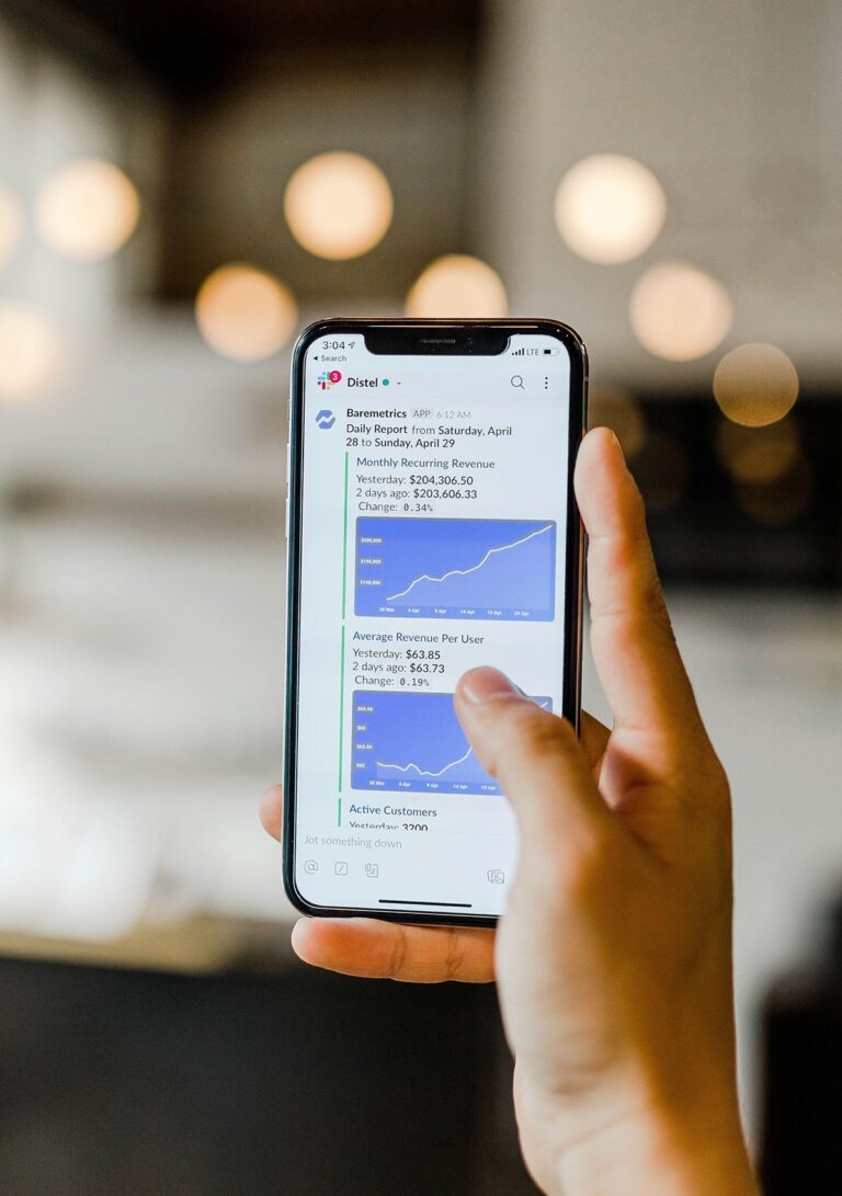 Person holding a smartphone displaying various business graphs and statistics.